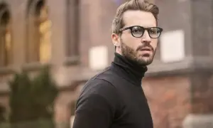 Mann mit Brille und Bart, dessen old money style herren haare perfekt sitzen.