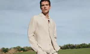 Mann in beigem Sakko und kariertem Hemd, lässig mit den Händen in den Hosentaschen. Perfekt, um ein beiges Sakko zu kombinieren für einen stilvollen Look.