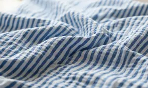 Blau-weißer Seersucker-Stoff mit charakteristischen Falten. Dieses Gewebe ist leicht und luftig, ideal für Sommerkleidung.