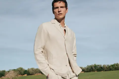 Mann in beigem Sakko und kariertem Hemd, lässig mit den Händen in den Hosentaschen. Perfekt, um ein beiges Sakko zu kombinieren für einen stilvollen Look.
