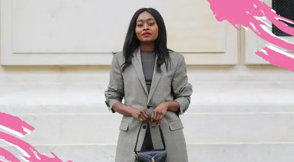 Frau in schickem Business-Outfit mit kariertem Blazer und schwarzer Handtasche, bereit für ein wichtiges Meeting.