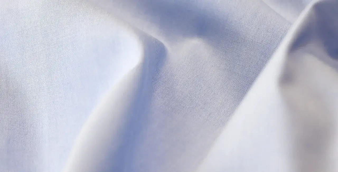 Feine, hellblaue Popeline-Webart, die sich sanft im Licht kräuselt.
