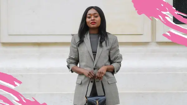 Frau in schickem Business-Outfit mit kariertem Blazer und schwarzer Handtasche, bereit für ein wichtiges Meeting.